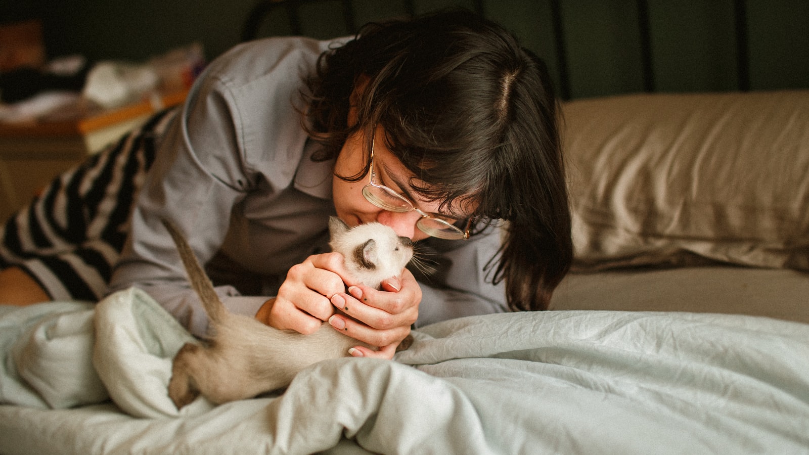 a woman is petting a cat on the bed