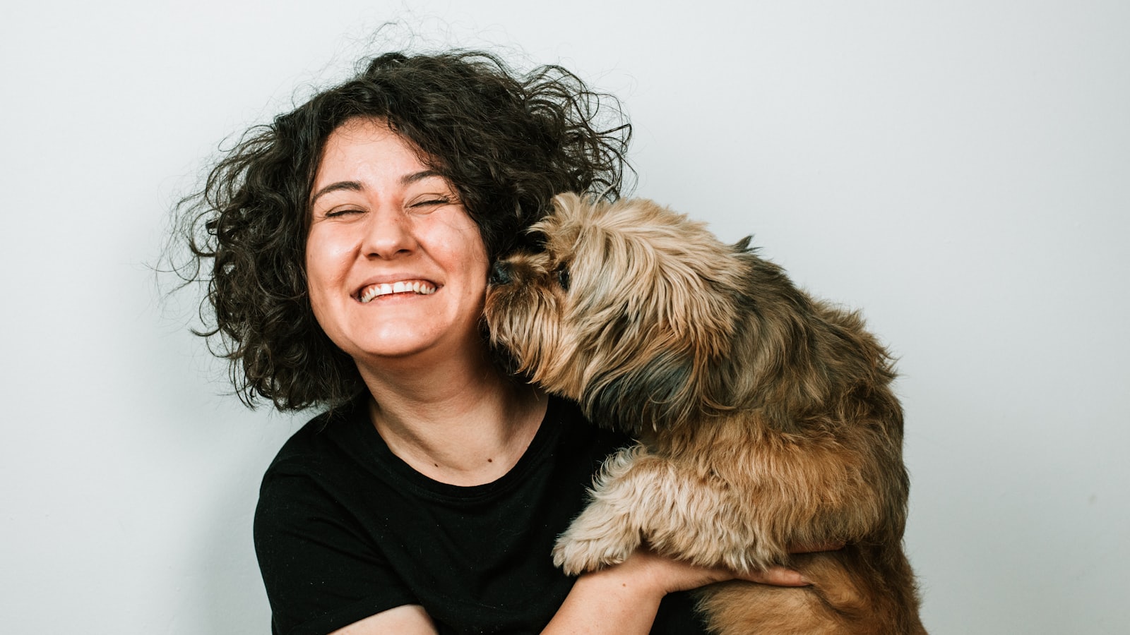 dog kissing woman in black crew-neck shirt