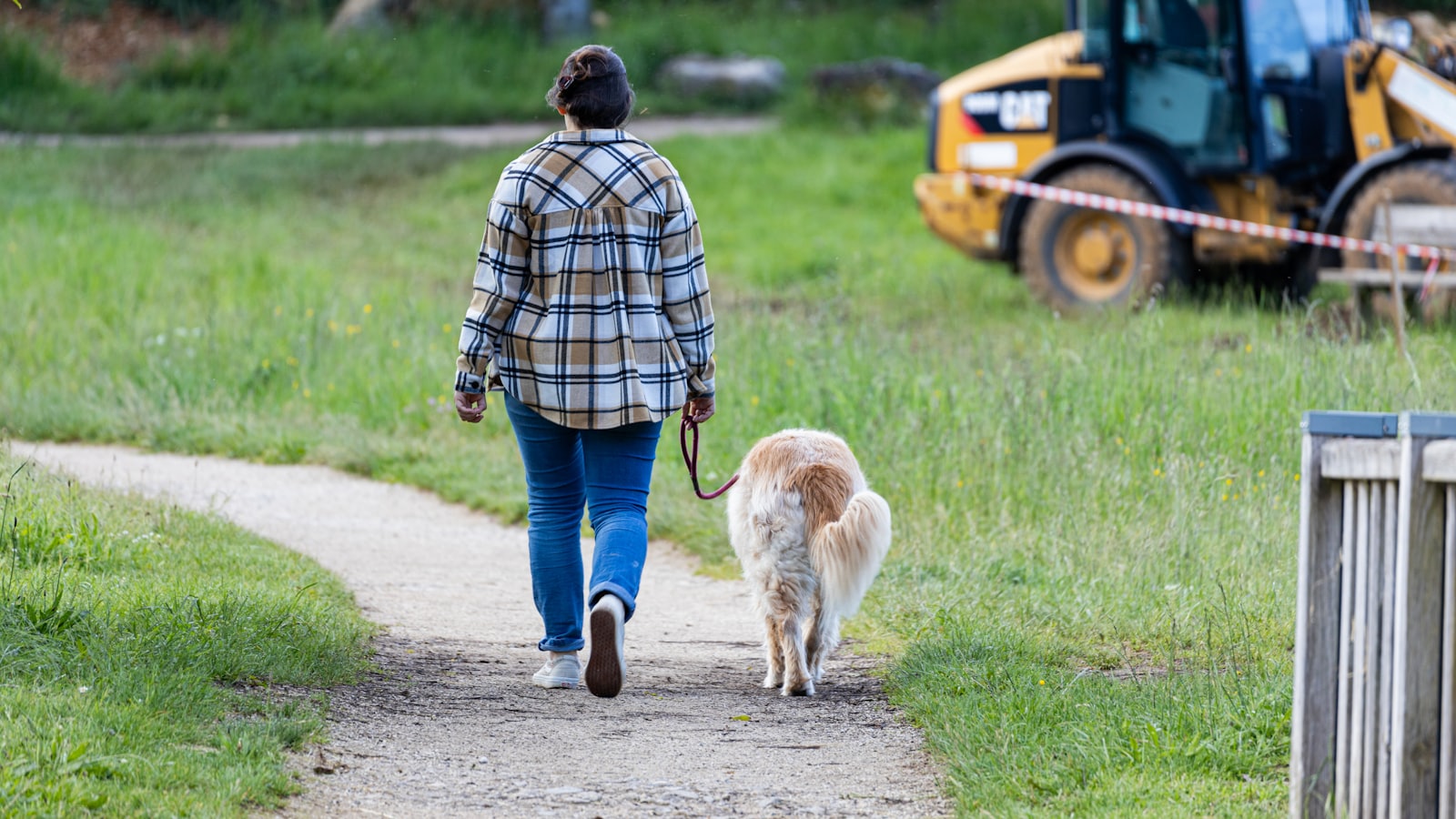a woman walking a dog down a dirt road