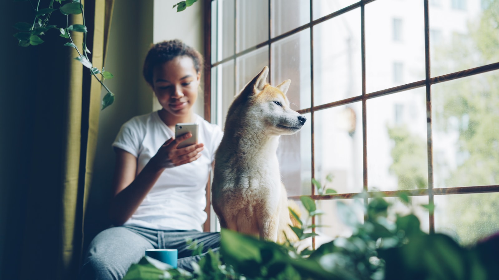 Woman and dog look out a window together.