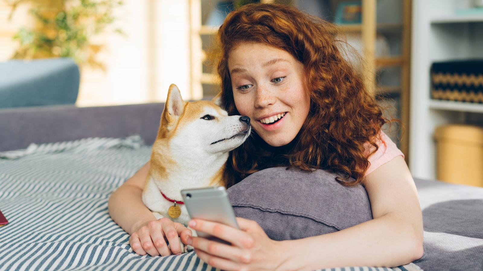 a woman laying on top of a bed next to a dog