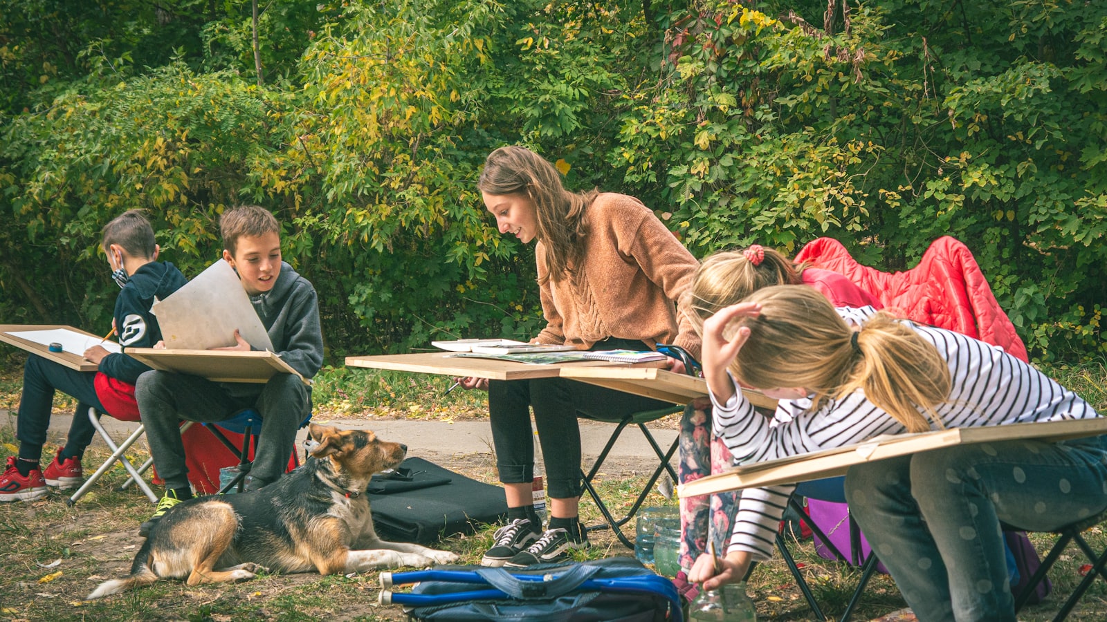 People sketching outdoors with a dog nearby
