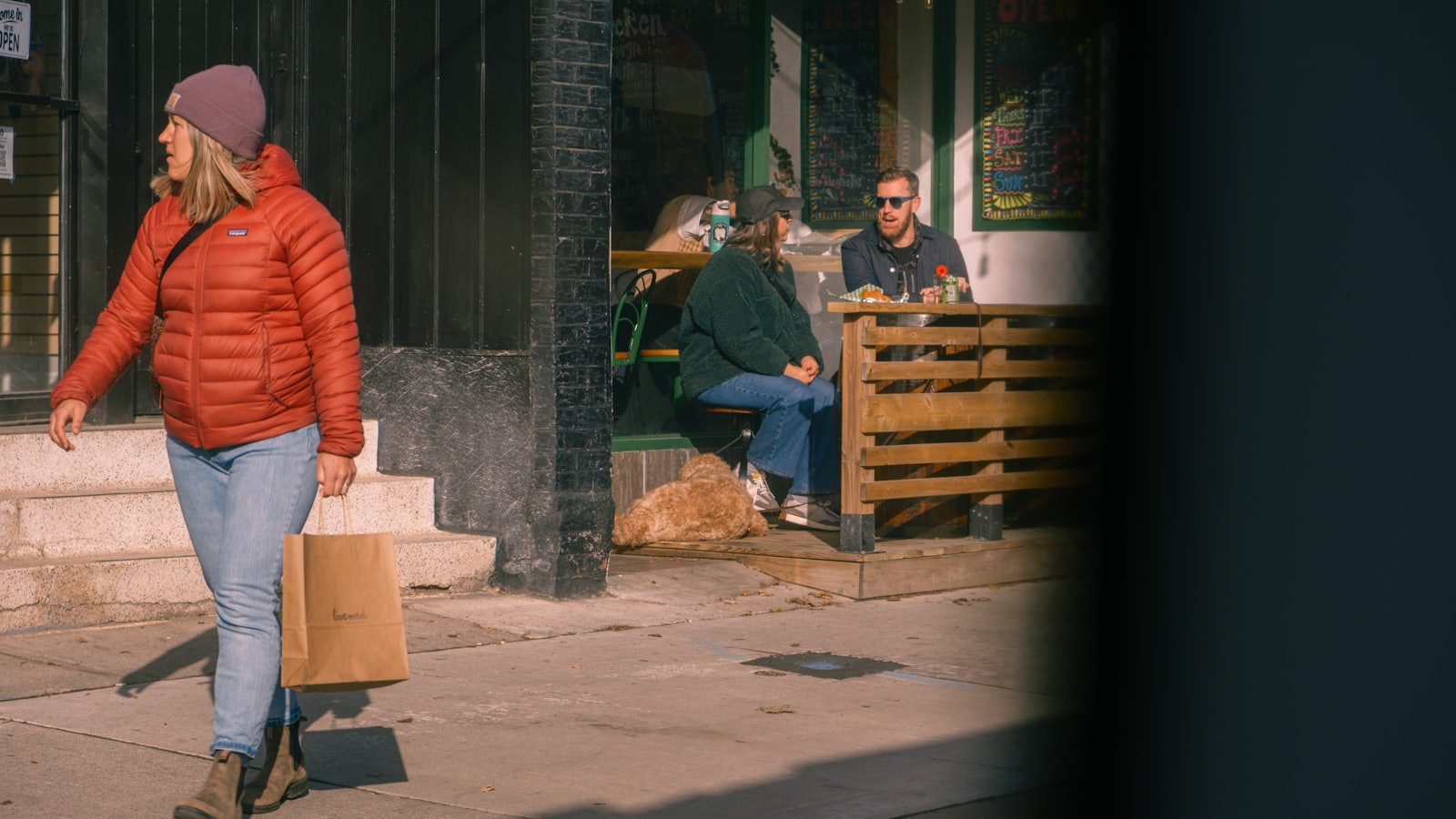 Woman walks past cafe with patrons seated outside
